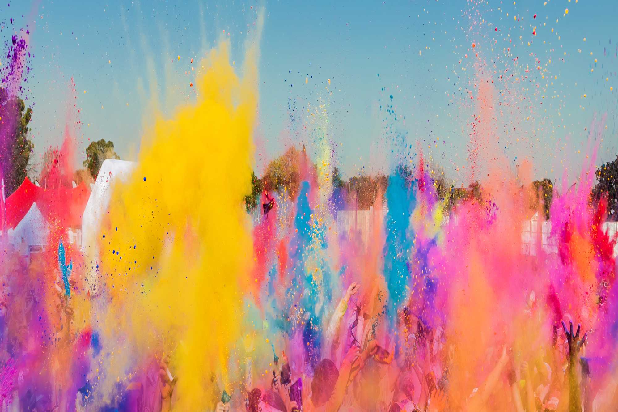 Crowd throwing bright colored powder paint in the air