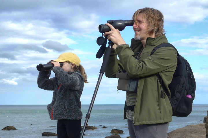 father_and_daughter_watching_with_bionoculars_on_the_beach