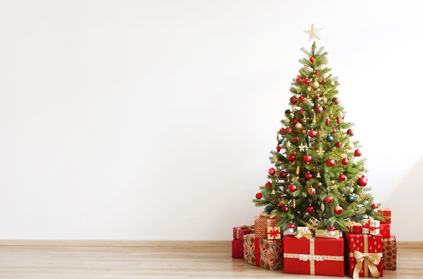 Christmas tree in a white room, with red presents sitting underneath