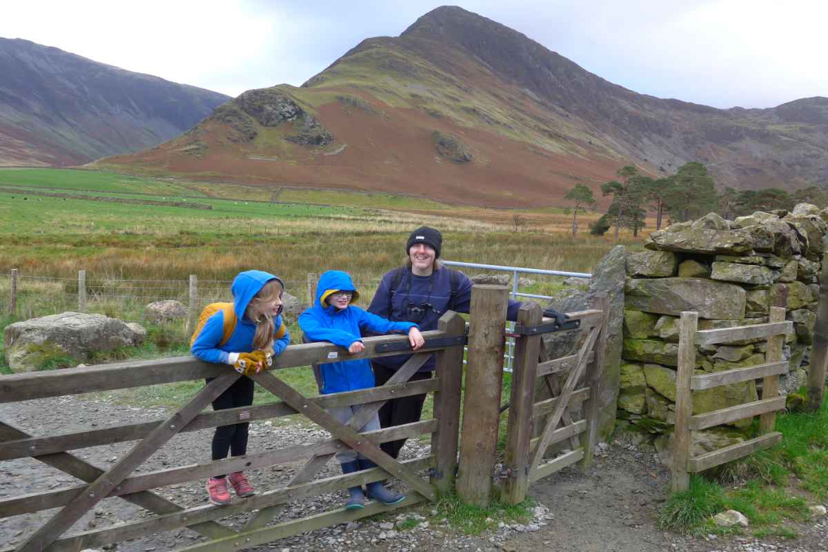 Man and two kids stood at a gate in the Lake District