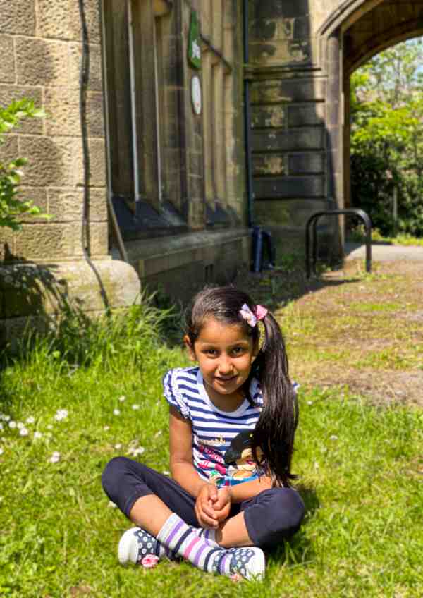 A young girl sat on the grass outside