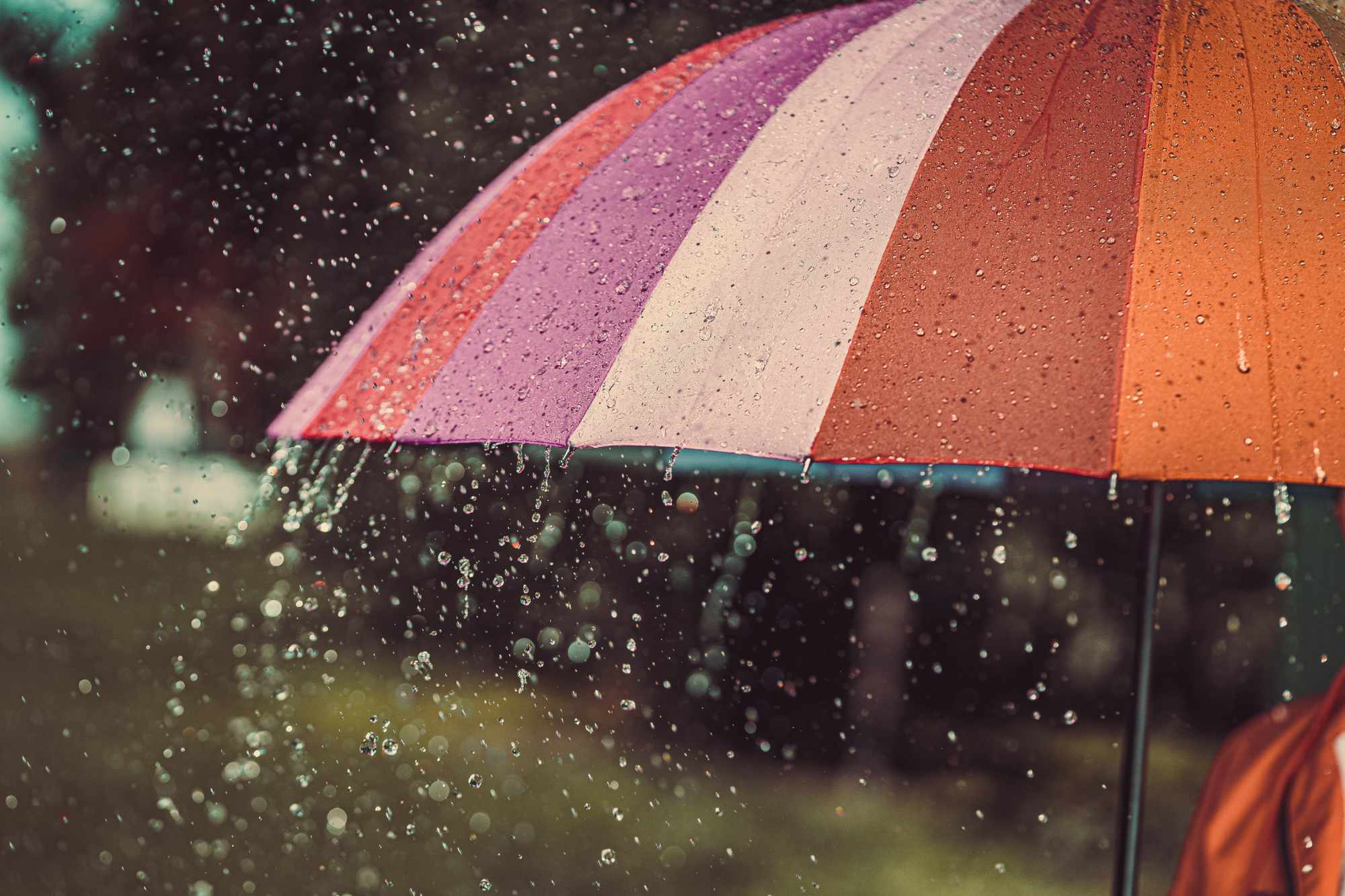 Bright colored rainbow umbrella in the rain autumn weather