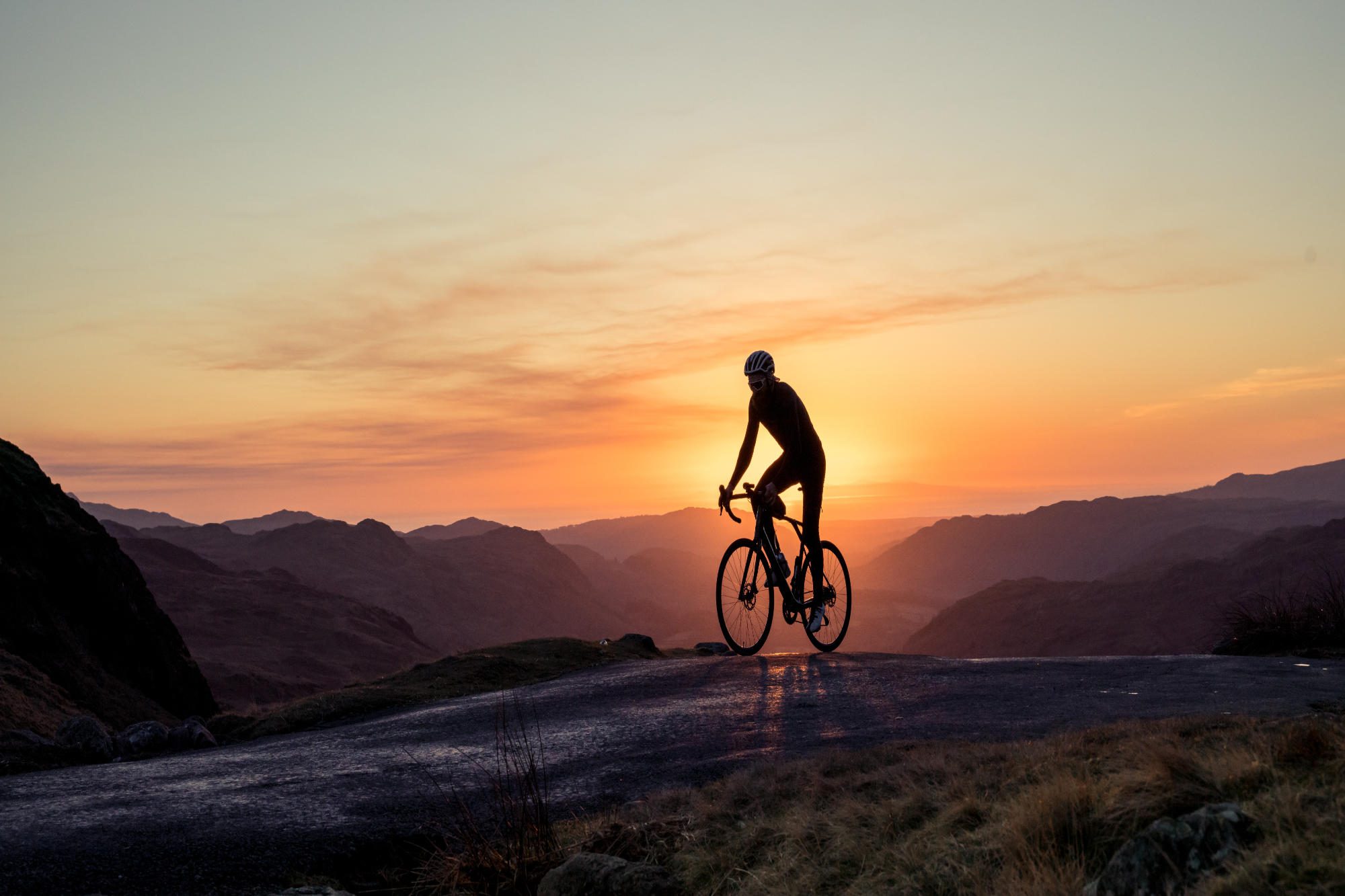 A man cycling on a track at sunset