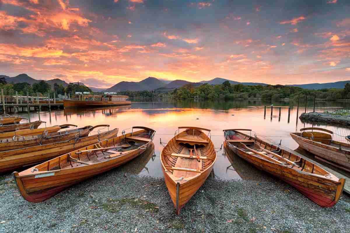 A fiery sunset over boats on the shore of Derwentwater at Keswick in the Lake District in Cumbria