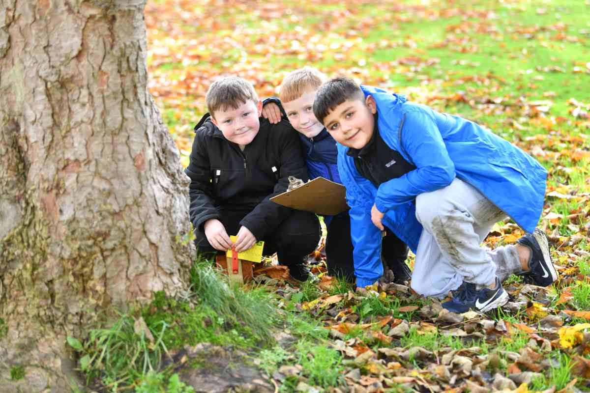 Three school children connecting with nature on a school trip